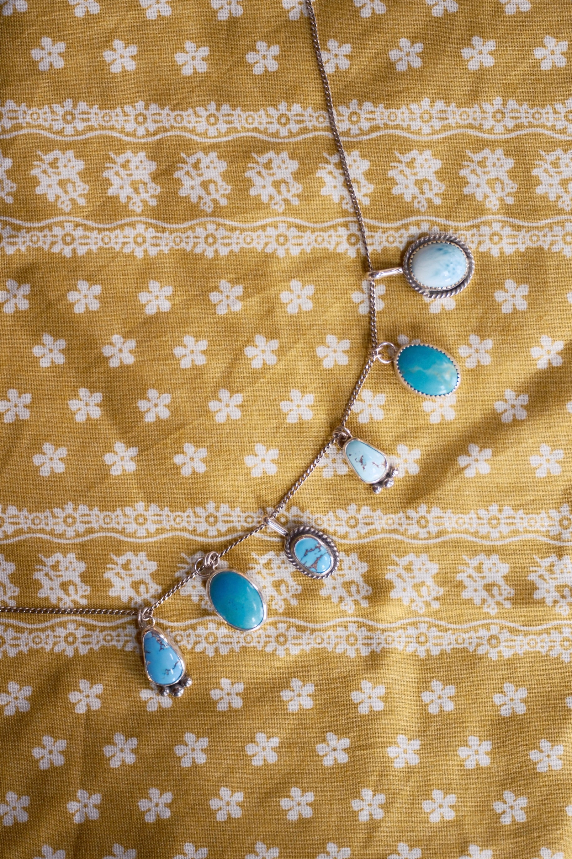 Necklace with blue stones on a yellow fabric background